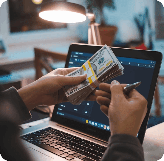 Person counting cash next to a laptop